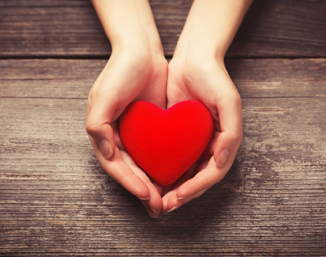 Corazón rojo sostenido entre manos